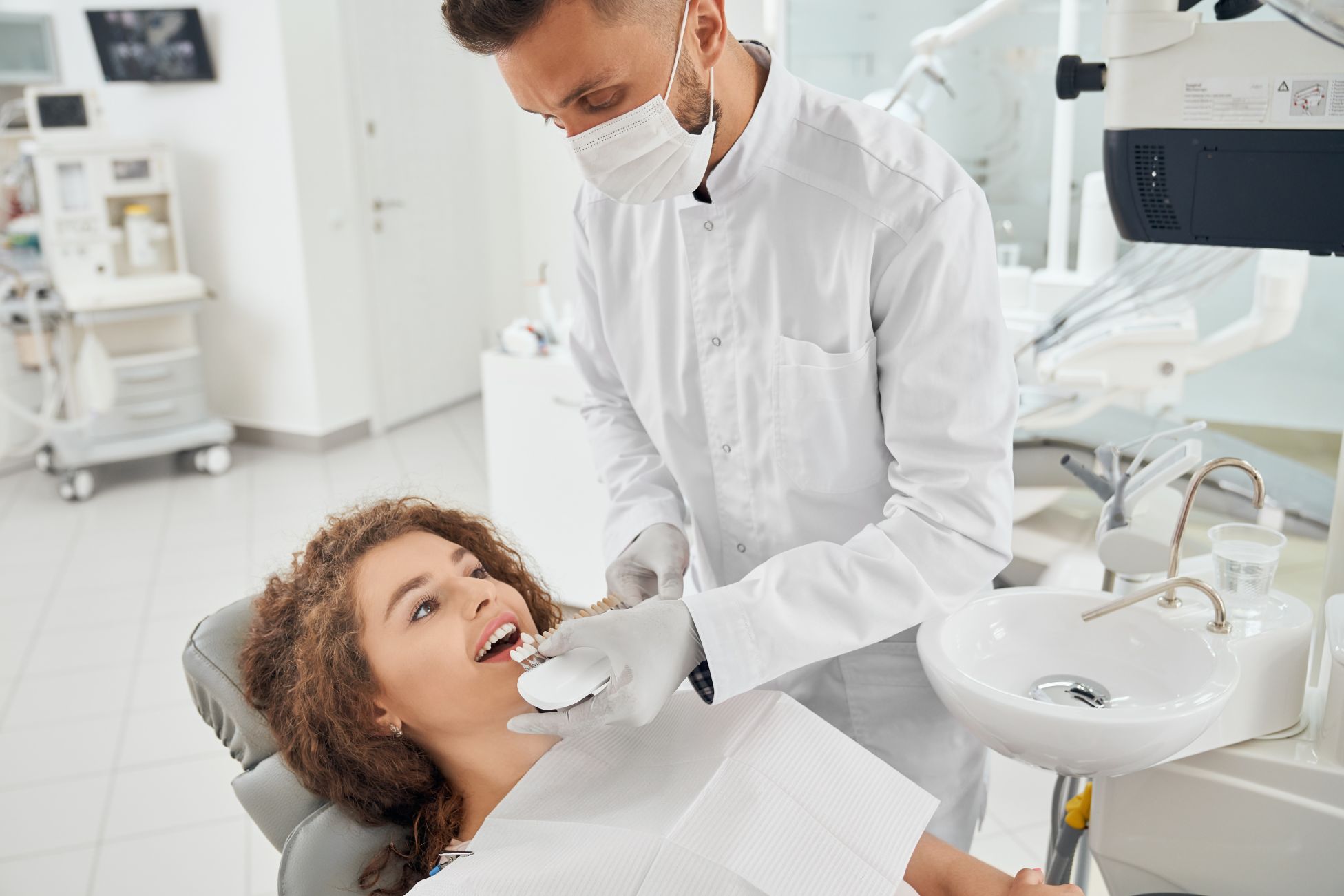 woman-smiling-while-male-dentist-keeping-teeth-color-range